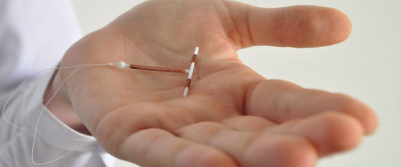 Holding an IUD birth control copper coil device in hand, used for contraception - side view